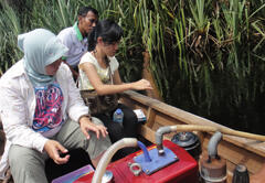 Sampling river water from a boat to collect water-dwelling microorganisms (in this case, microalgae)