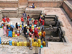 People gathering at a communal water fountain.