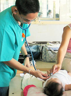 Examining an infant with pneumonia at a regional hospital in the Philippines